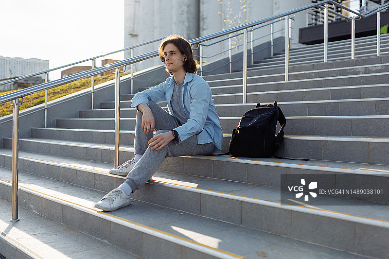 白天坐在楼梯上的休闲年轻男游客图片素材