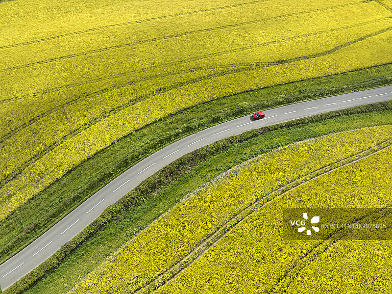 红色汽车在乡村道路上行驶图片素材