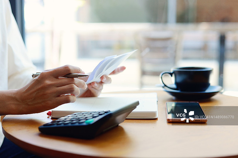 年轻的亚洲女性管理个人银行和财务，她正在计划预算，计算支出，并使用计算器查看账单图片素材