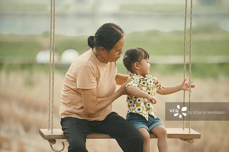 亚洲祖母和孙子在乡间户外玩秋千，祖孙同乐图片素材