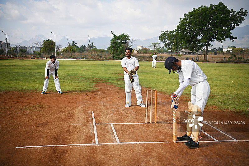 球场上的板球击球手和准备接球的守门员图片素材