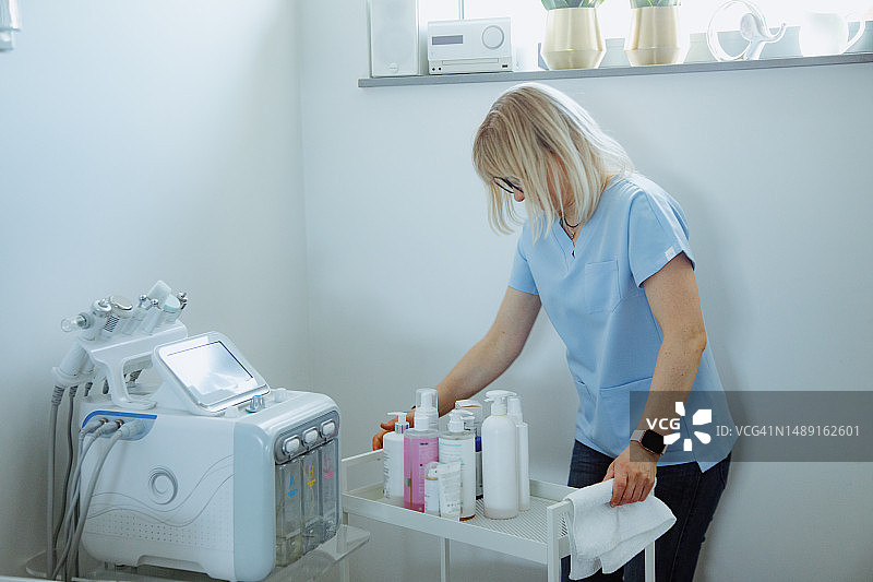 经验丰富的女美容师整理水疗仪器的产品，准备清洁程序图片素材