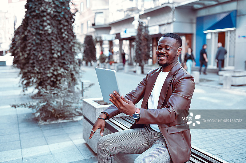 在户外长椅上进行视频会议的非洲男士图片素材
