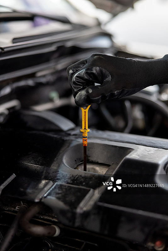 修理工在车库测量汽车的油位图片素材