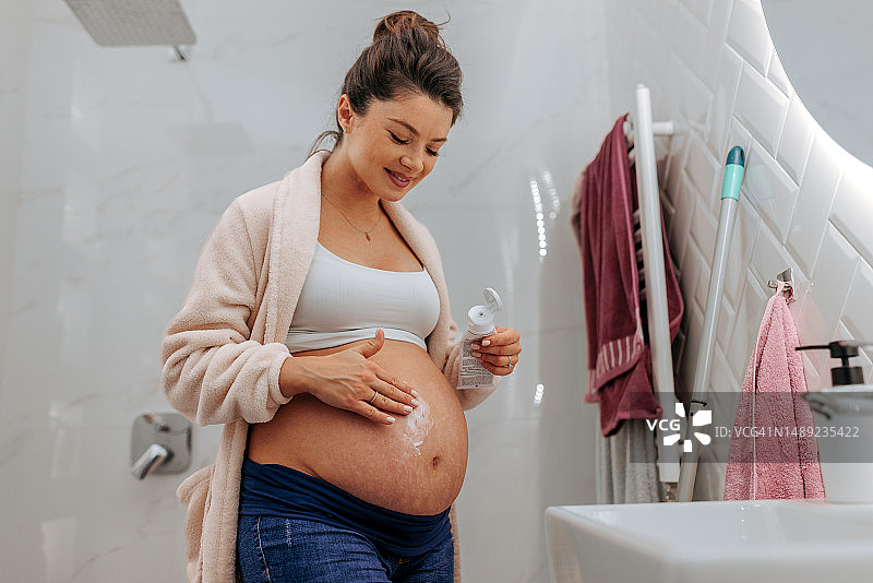 孕妇在腹部涂抹润肤霜图片素材