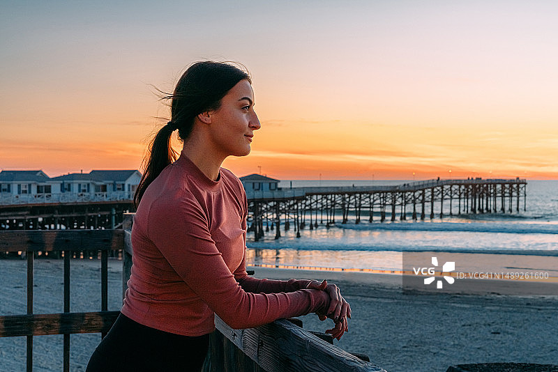 在太平洋海滩水晶码头看日落的慢跑女人图片素材