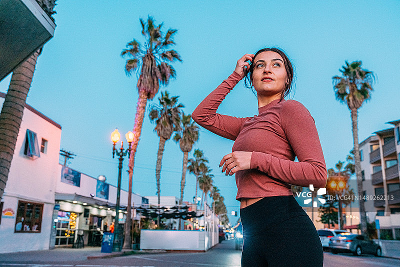 在加利福尼亚州圣地亚哥太平洋海滩附近街道上跑步的年轻女子图片素材