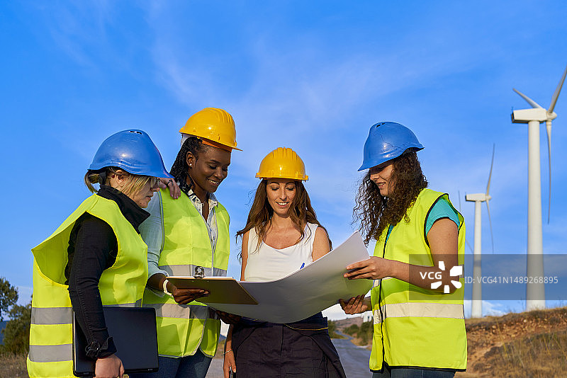 四个戴着护胸甲和头盔的女人在看建筑图纸图片素材