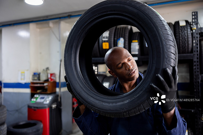 维修车库：技工更换轮胎并拿着新轮胎图片素材