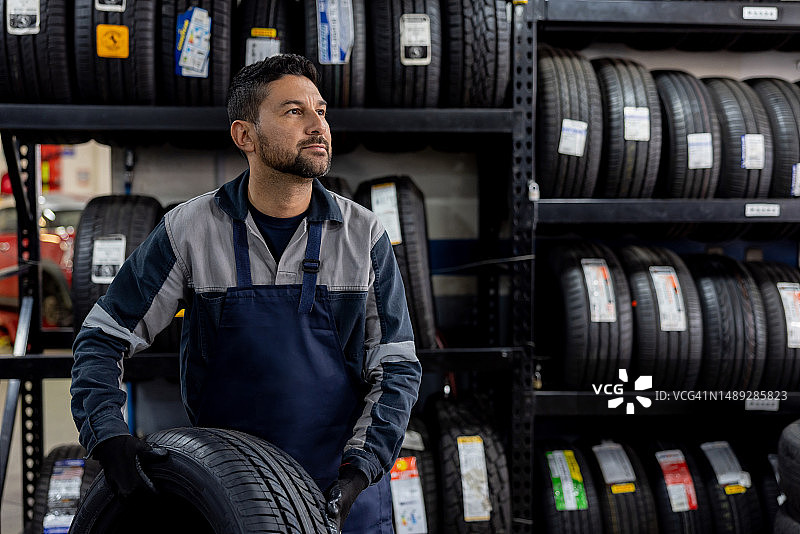 技工在修理厂更换轮胎并搬运车轮图片素材