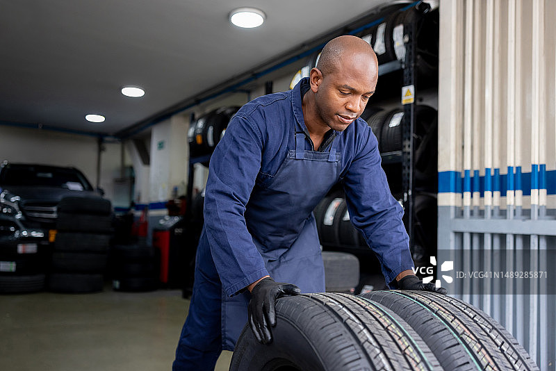 修理工在汽车修理店移动轮胎图片素材