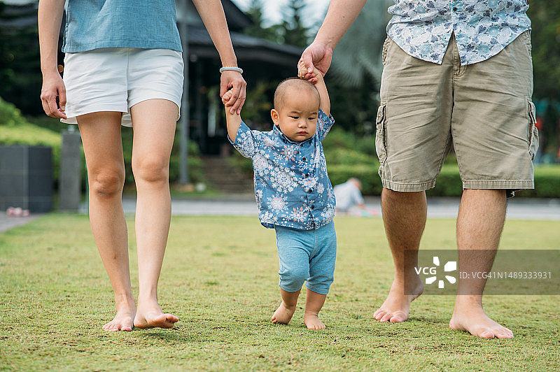 父母帮助儿子学习走路图片素材