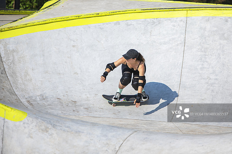 年轻女子在夏季的滑板公园玩滑板图片素材