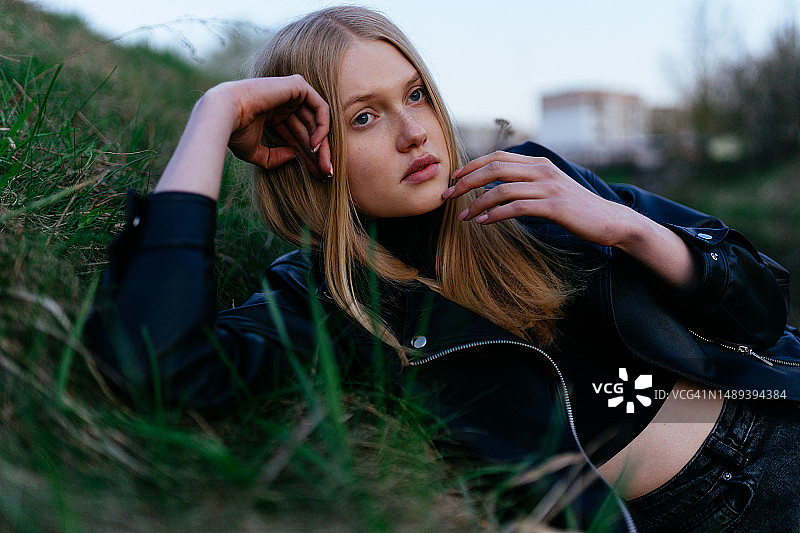 穿着皮夹克的女人躺在草地上图片素材