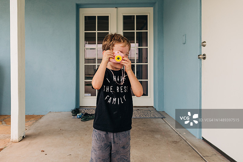 在后院用玩具相机玩耍的四岁白人男孩图片素材