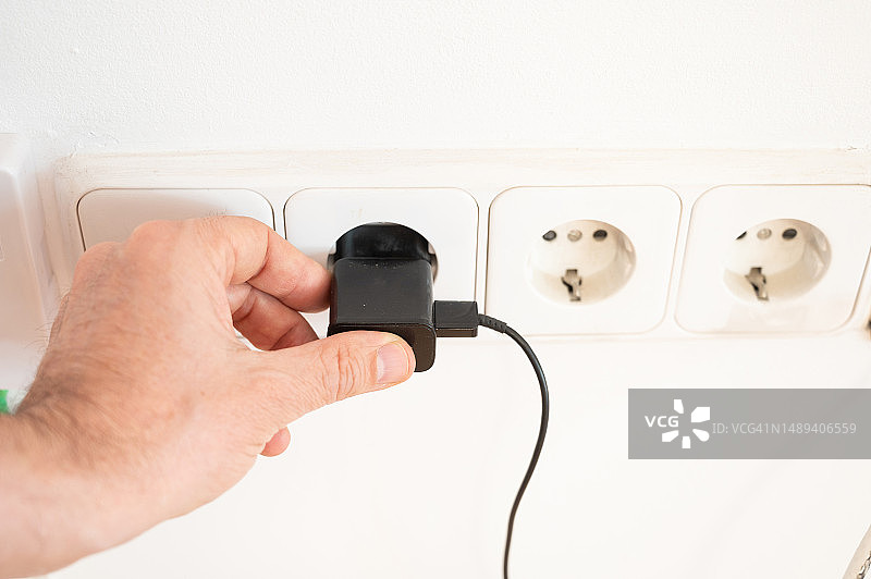 一个身份不明的男人正在插电源插座图片素材