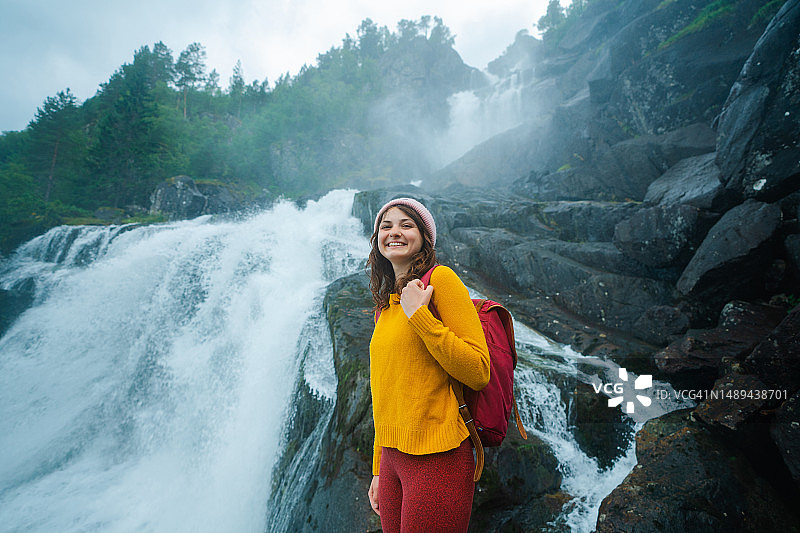 在挪威山区强大的瀑布附近行走的女人图片素材