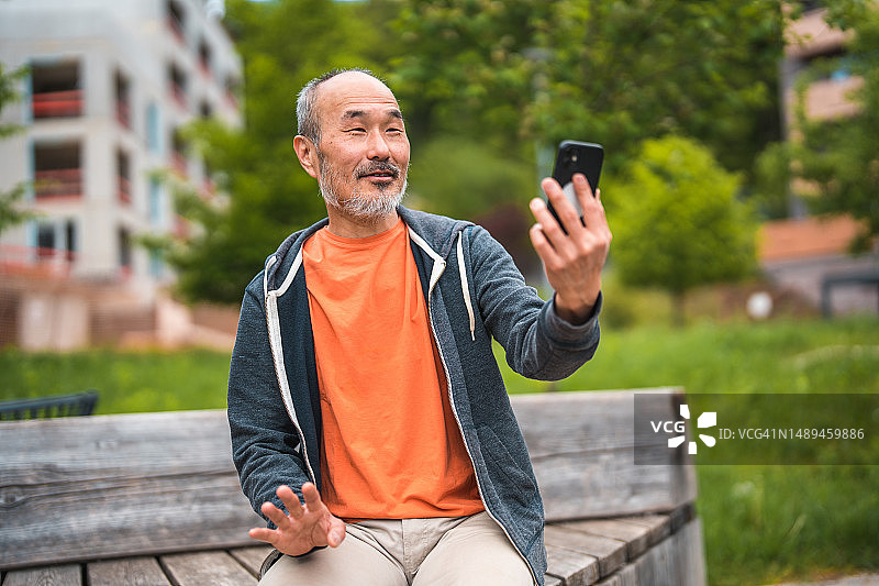 在公园使用智能手机的成熟亚洲男人图片素材