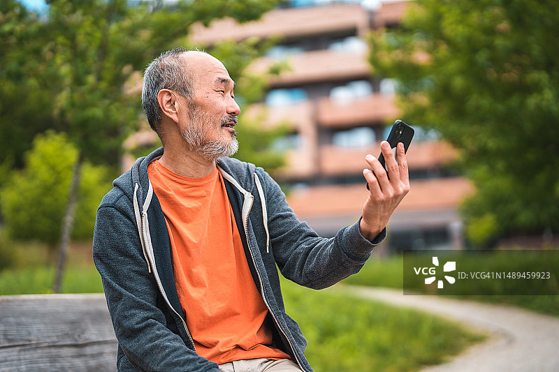 在公园使用智能手机的成熟亚洲男人图片素材