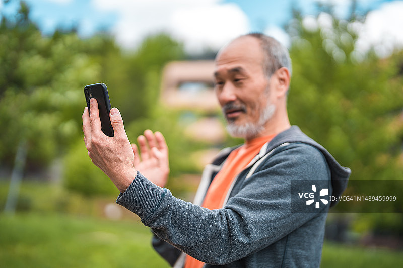 在公园里进行视频通话的快乐中年亚洲男人图片素材