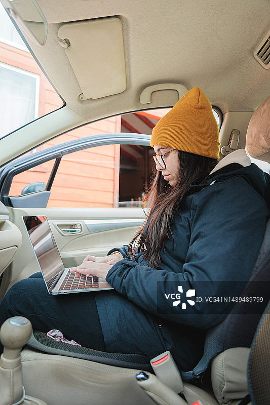 在车内用笔记本电脑进行远程工作的年轻白人女子图片素材