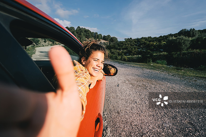 女视频博主开着电动汽车旅行，用智能手机为社交媒体录制视频图片素材