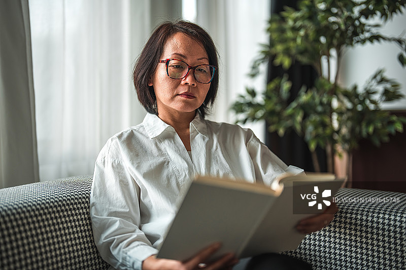 阅读书籍的亚洲中年女士图片素材