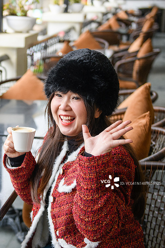 在咖啡馆享受时向人打招呼的快乐女孩肖像图片素材
