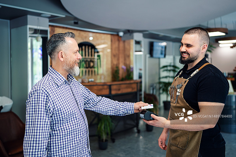 理发后对理发师付款的满意顾客图片素材