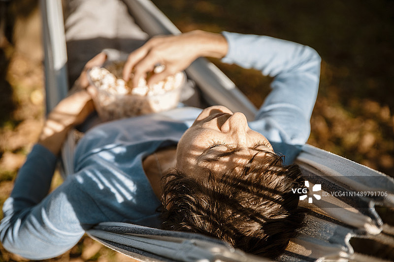 在吊床上吃着爆米花放松的女人图片素材