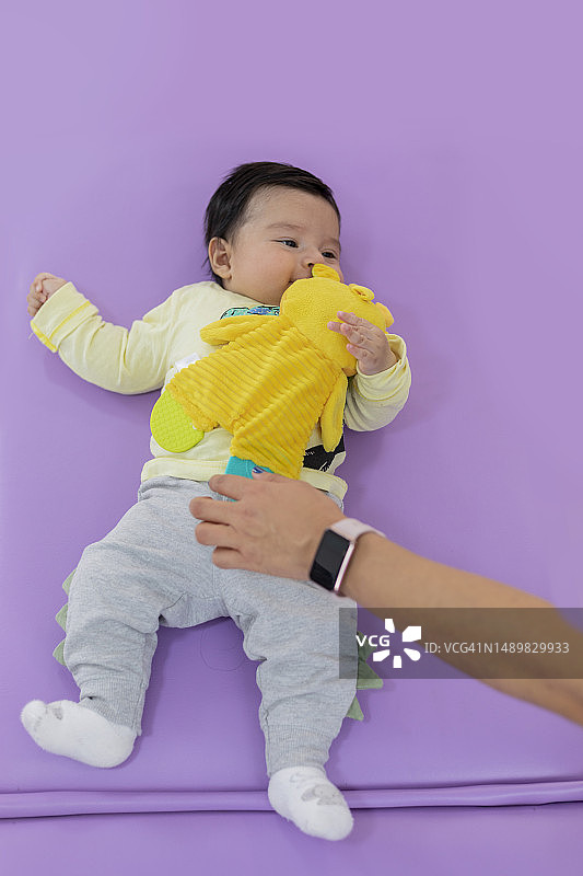 当婴儿躺在担架上时，把毛绒玩具递给他图片素材