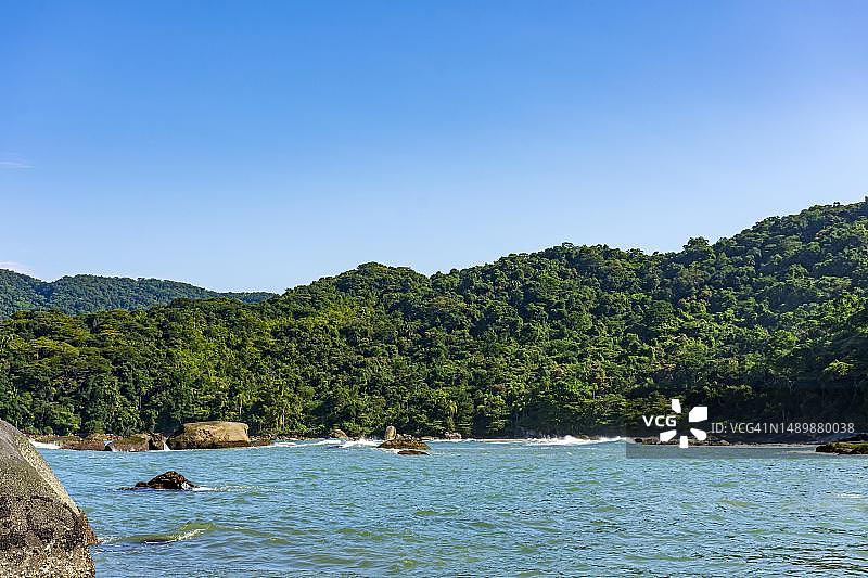 巴西圣保罗州贝尔蒂奥加沿海多岩石热带天堂海滩，群山环绕森林茂密图片素材