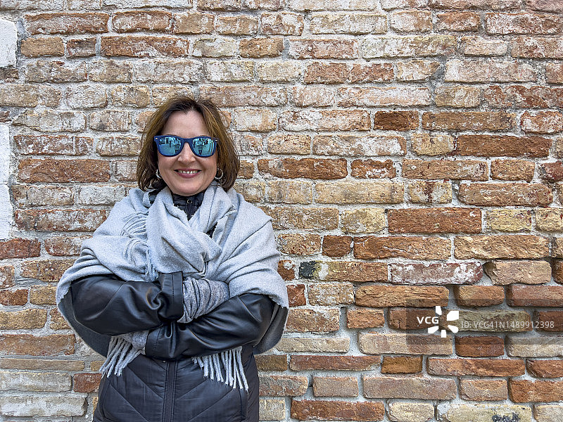 靠在砖墙上的女人，正面视角，半身照图片素材