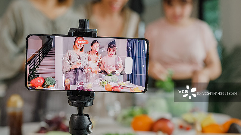 年轻亚洲女性朋友网红录制烹饪沙拉视频图片素材