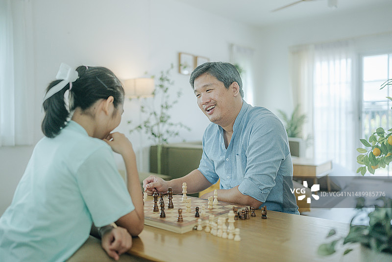 专心和女儿下棋的亚洲老年人图片素材