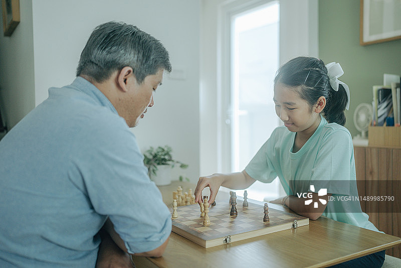 专心和女儿下棋的亚洲老年人图片素材