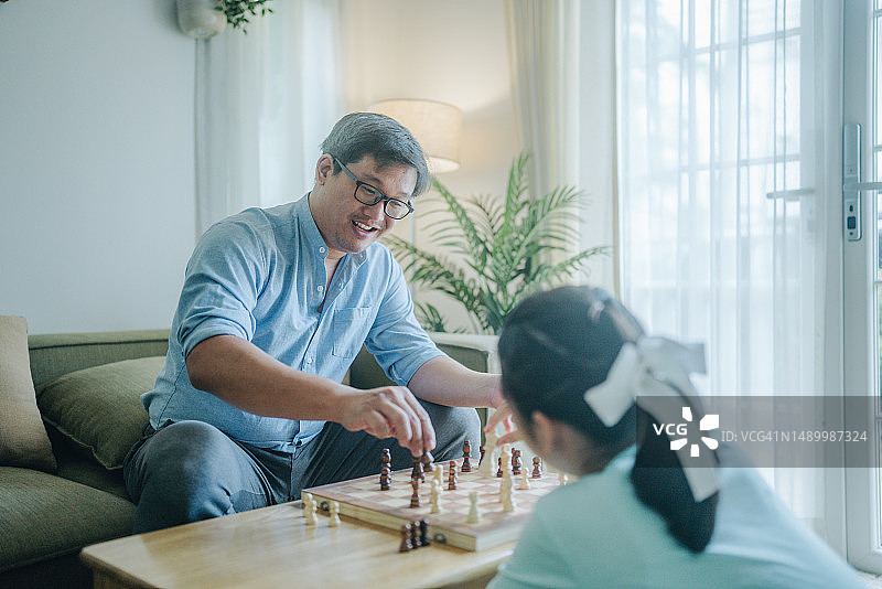 专心和女儿下棋的亚洲老年人图片素材