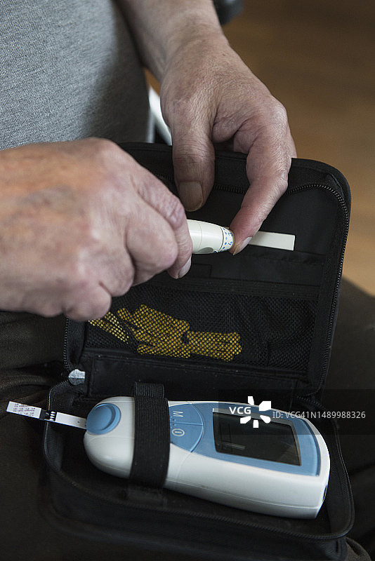 老年男人使用采血笔刺破手指图片素材