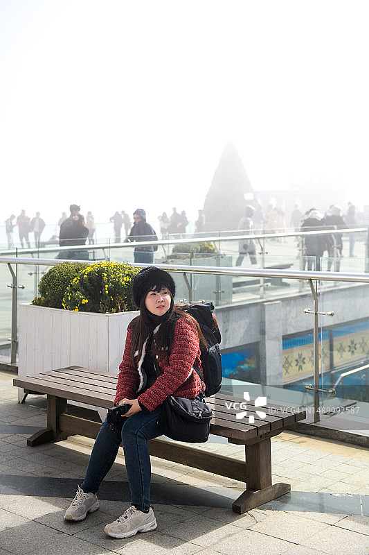 在雾天坐在长凳上的女游客图片素材