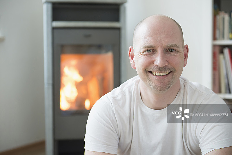 男子在壁炉旁的客厅里微笑的肖像照图片素材