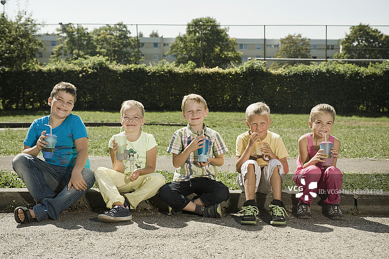 孩子们拿着马克杯坐在路边图片素材