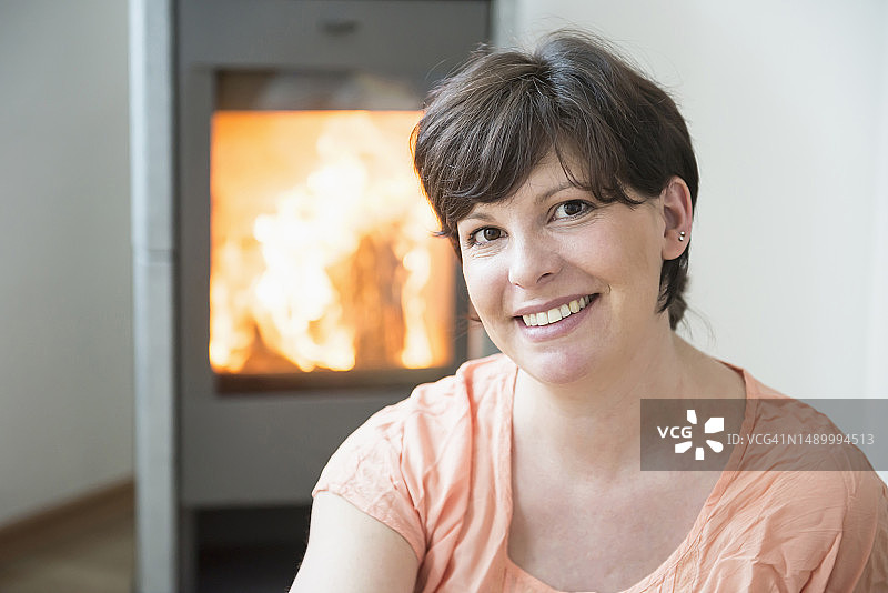 在带壁炉的客厅里微笑的女人肖像图片素材