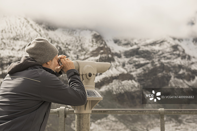 中年男人用望远镜看风景,格罗斯格洛克纳山与帕斯特泽冰川,位于奥地利克恩顿州Hohe Tauern国家公园图片素材