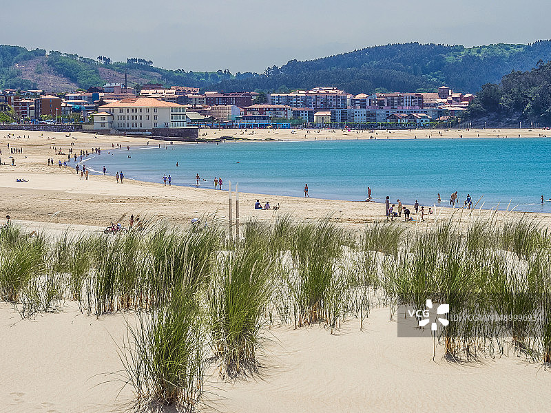 在有房屋和山丘背景的海滩上的人们图片素材