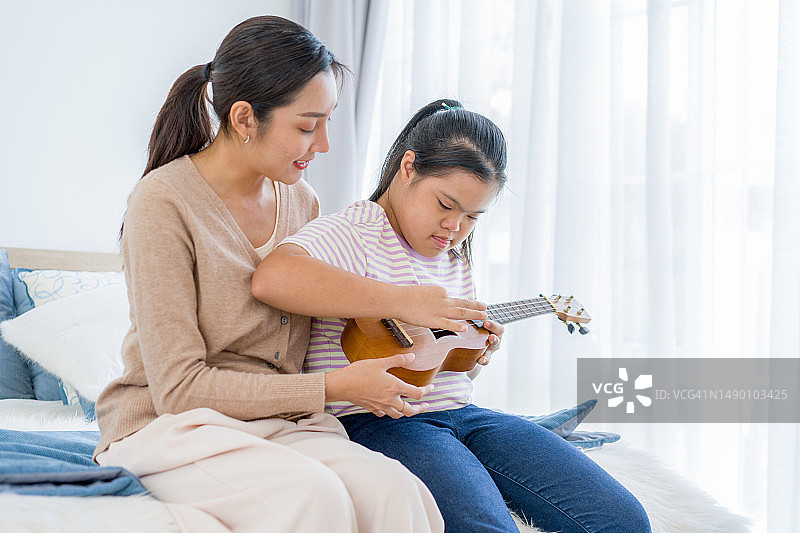 老师教患有唐氏综合征的女孩弹奏尤克里里图片素材