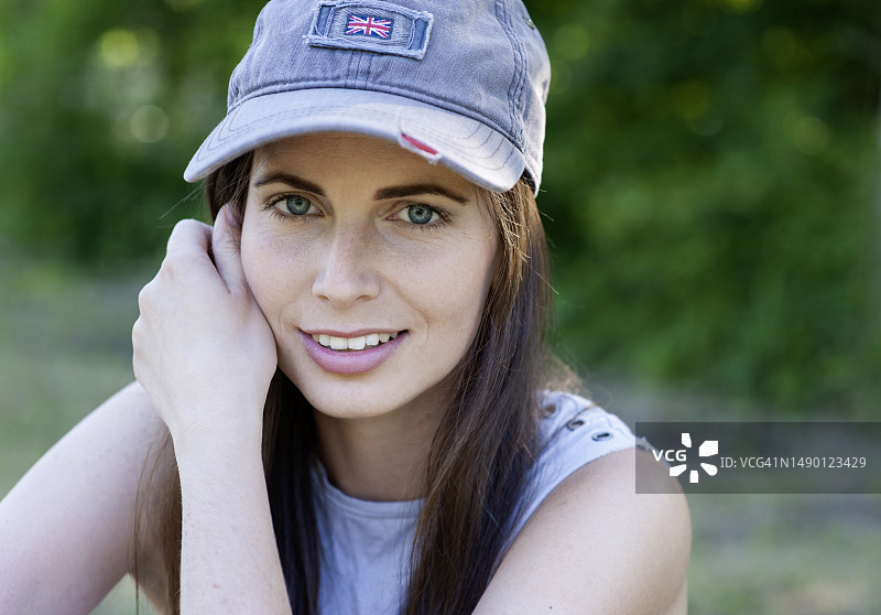 户外人像：戴棒球帽的棕色长发年轻女子图片素材