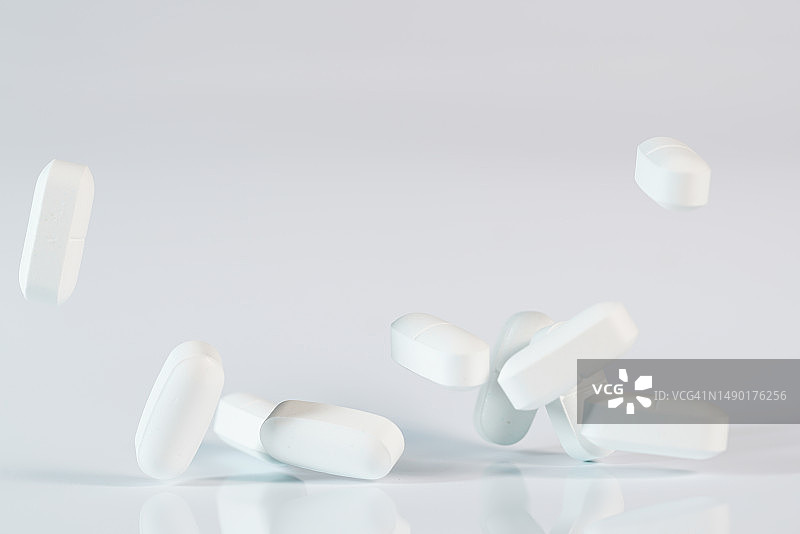 白色背景中飞在半空中的白色药丸图片素材