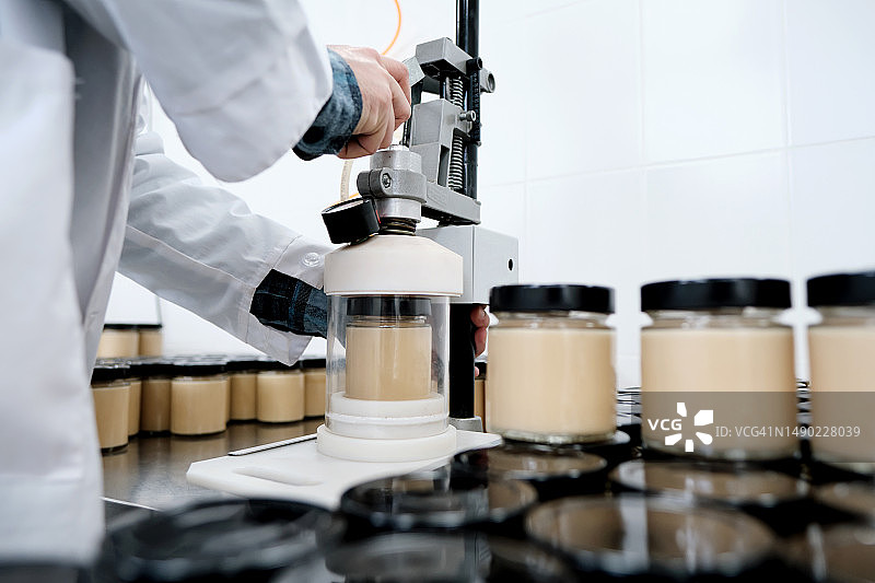 工厂工人用吸尘器清洁玻璃罐中的成品图片素材