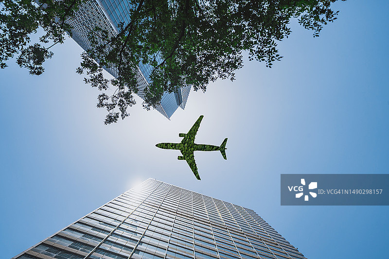 低角度拍摄：绿色飞机飞过商务办公楼图片素材