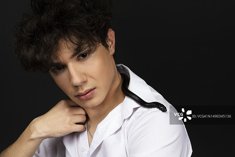 脖子上缠绕着黑蛇的年轻帅气男子图片素材